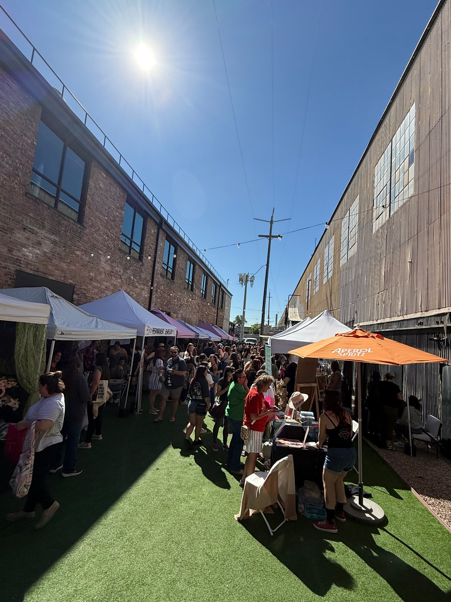 Outdoor event with tents and people under a clear blue sky.